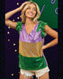 Woman wearing a colorful sequin top with green, gold, and purple in front of a festive background.