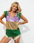 Woman wearing a colorful sequin top with green, purple, and gold sections on a white background