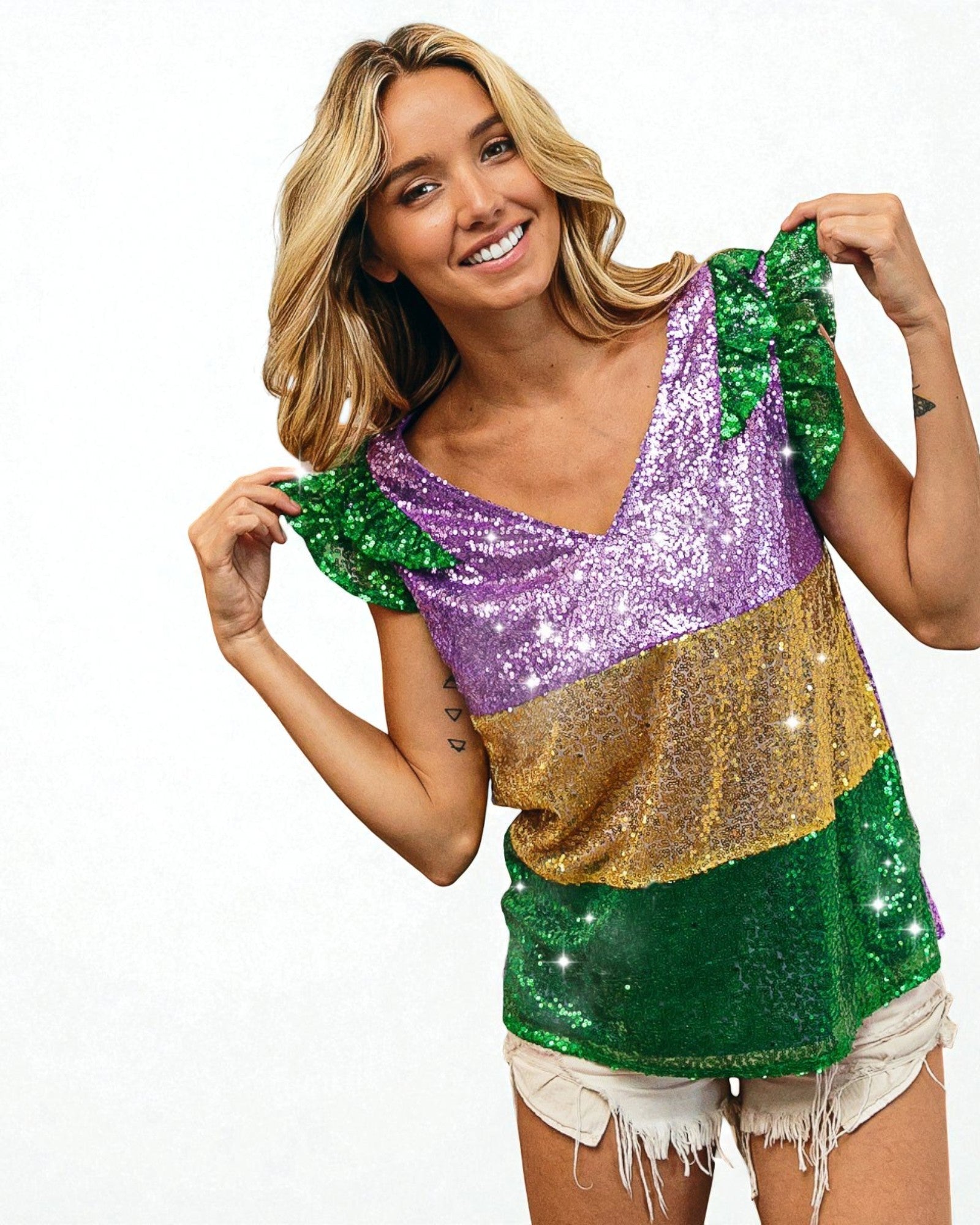 Woman wearing a colorful sequin top with green, purple, and gold in a festive setting.