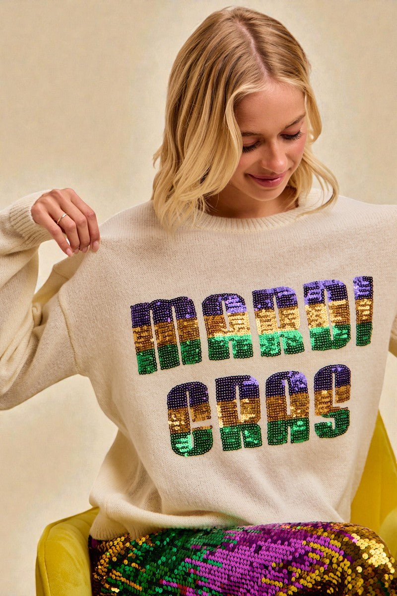 Woman wearing a sweater with colorful sequin text on a beige background