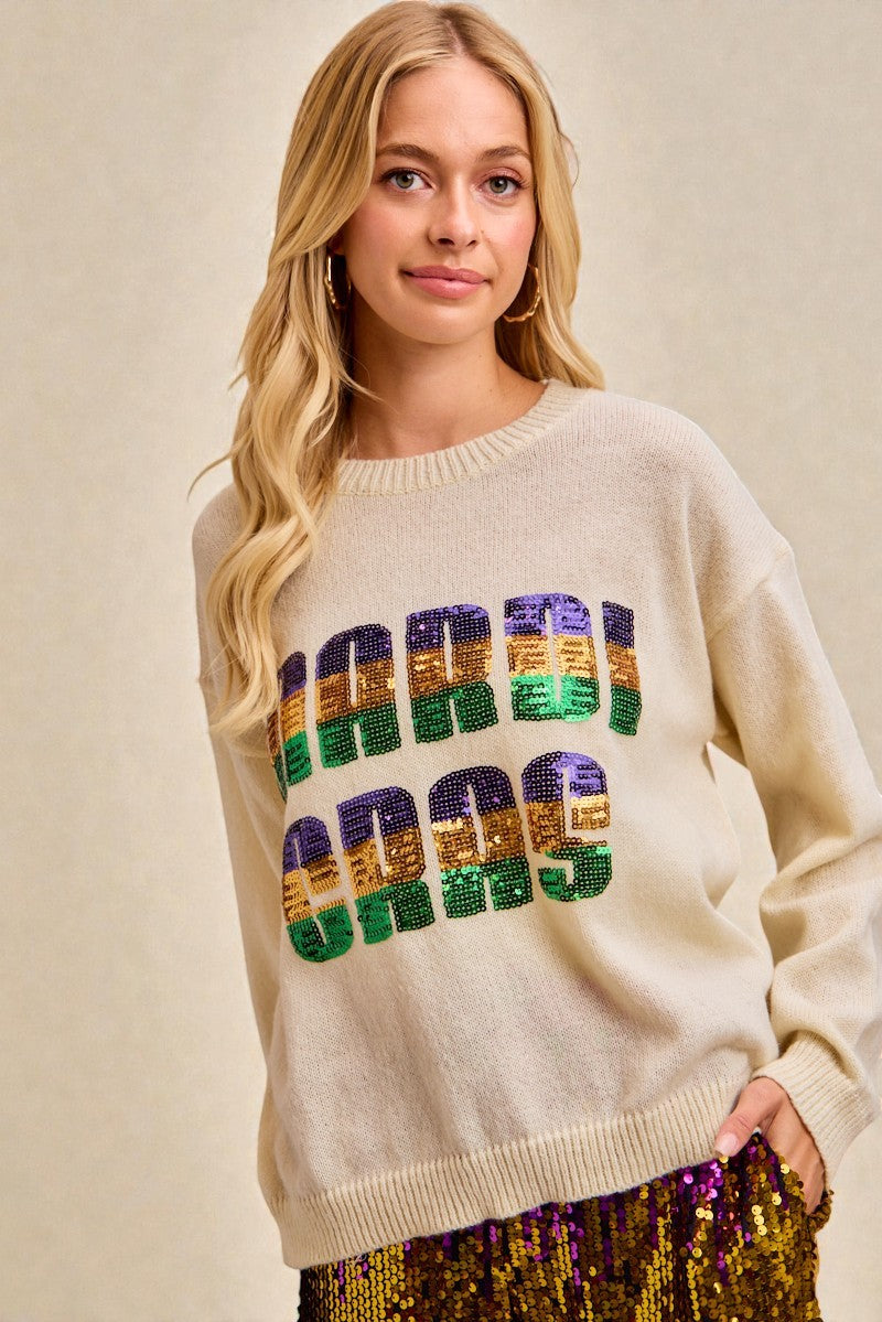 Woman wearing a beige sweater with colorful text design on a beige background