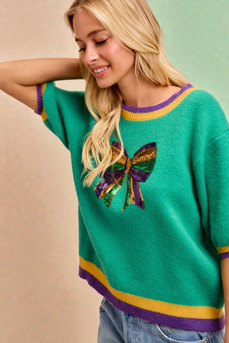 Woman wearing a green sweater with a colorful butterfly design on a beige and green background