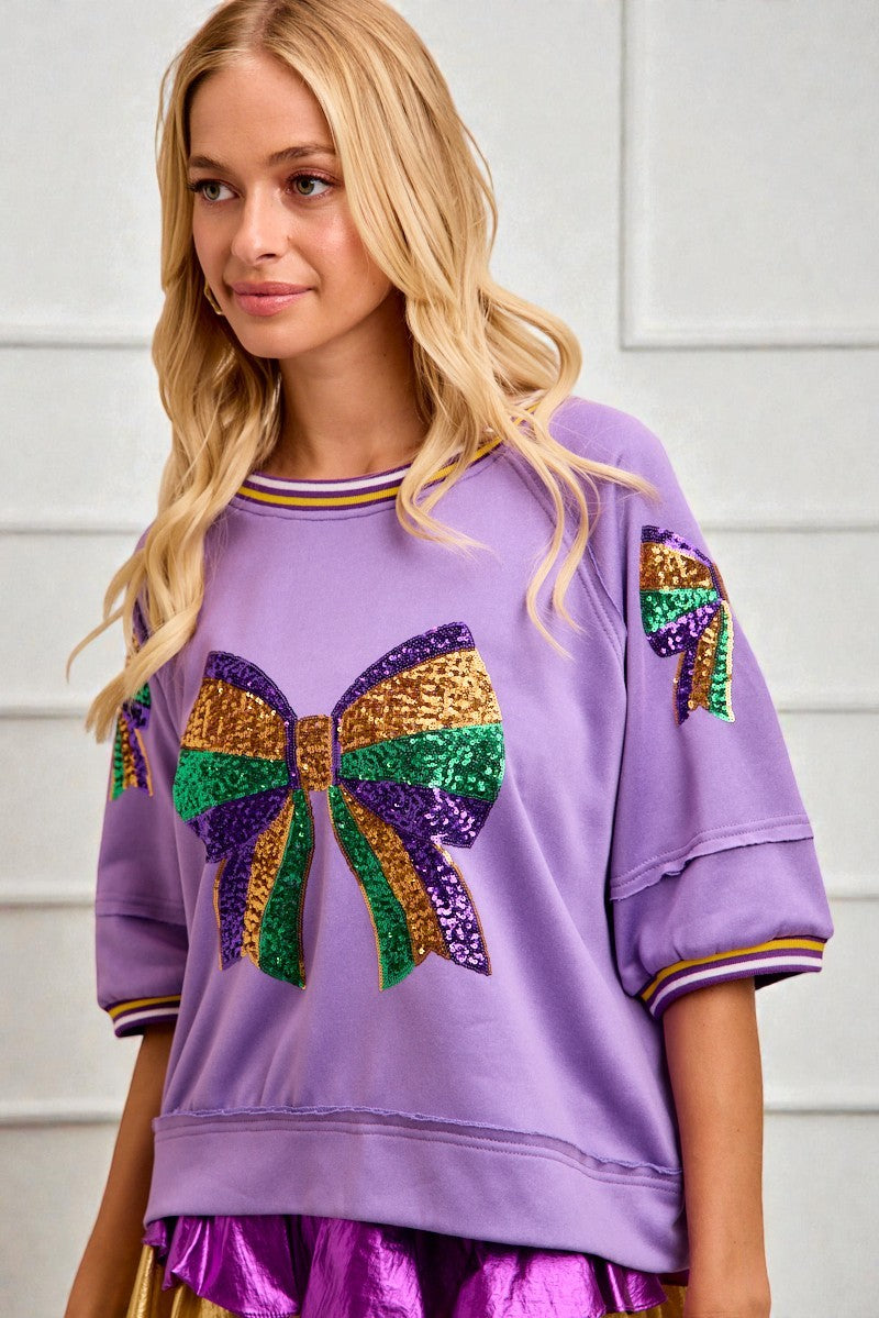 Woman wearing a purple sweatshirt with a colorful bow design on a white background