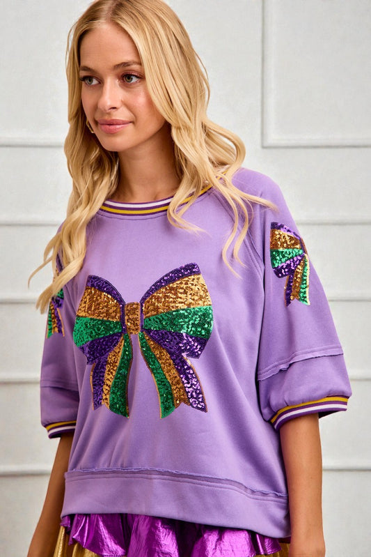 Woman wearing a purple sweatshirt with a colorful bow design on a white background