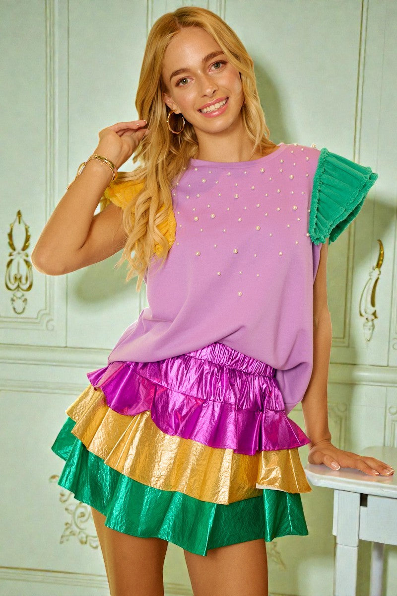 Woman wearing a colorful dress with ruffled layers in a decorative room.