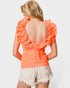 Woman wearing an orange ruffled top and beige shorts on a white background