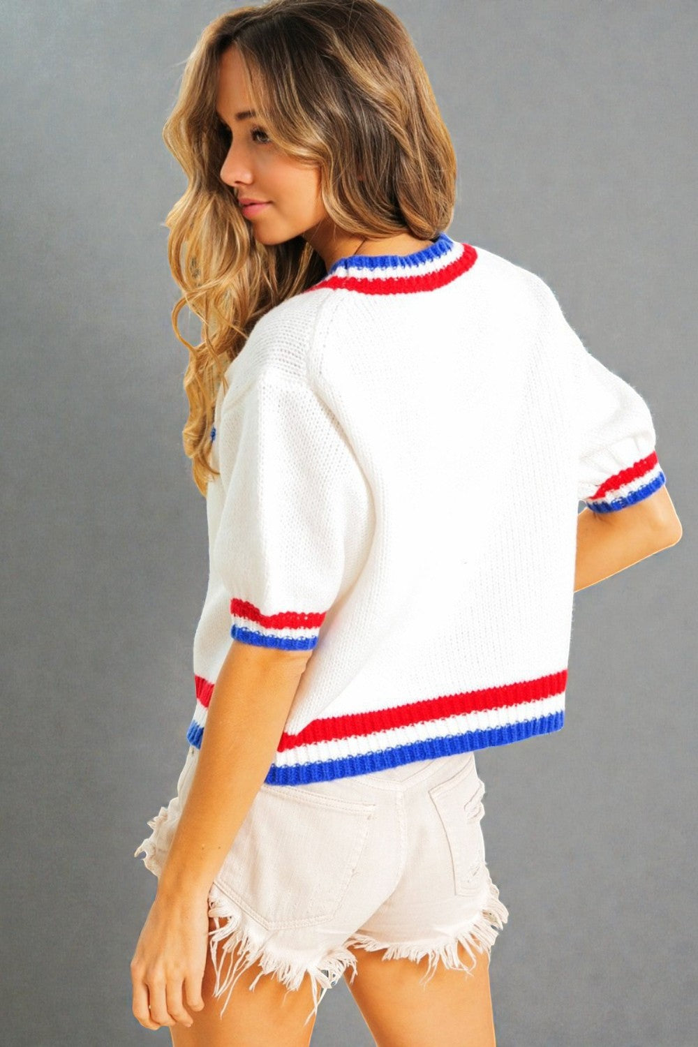 Woman wearing a white sweater with red and blue stripes on a gray background