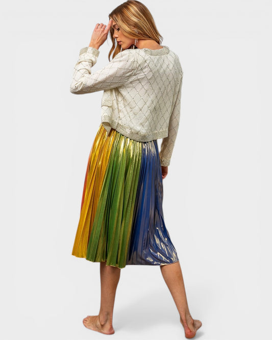 Woman wearing a light green sweater and colorful pleated skirt on a white background