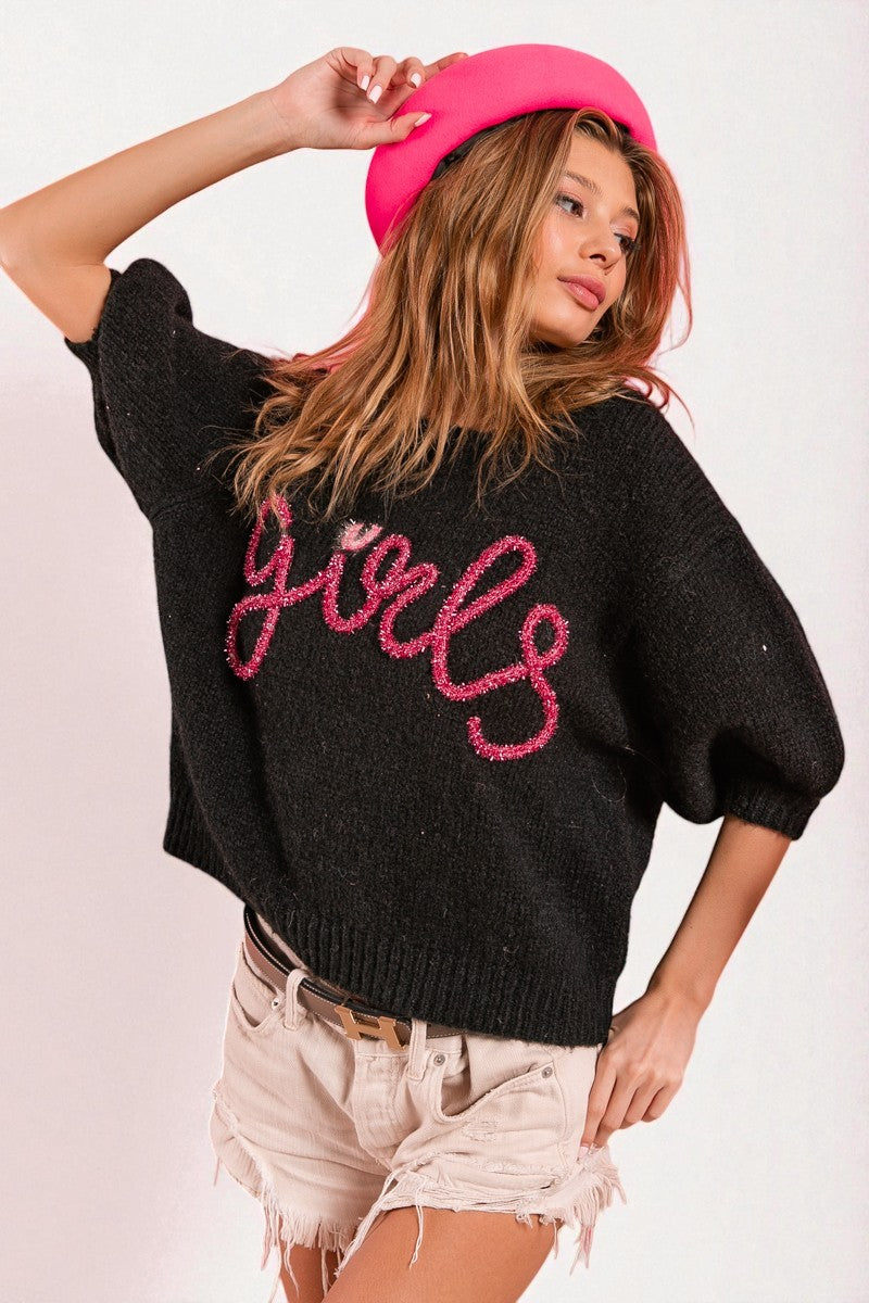 Woman wearing a black sweater with pink text and a pink beret on a white background