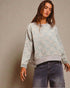Person wearing a light blue checkered sweater and jeans against a beige background