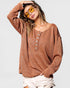 Woman wearing a brown long-sleeve top with buttons on a light gray background
