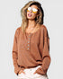 Woman wearing a brown sweater with a plain background