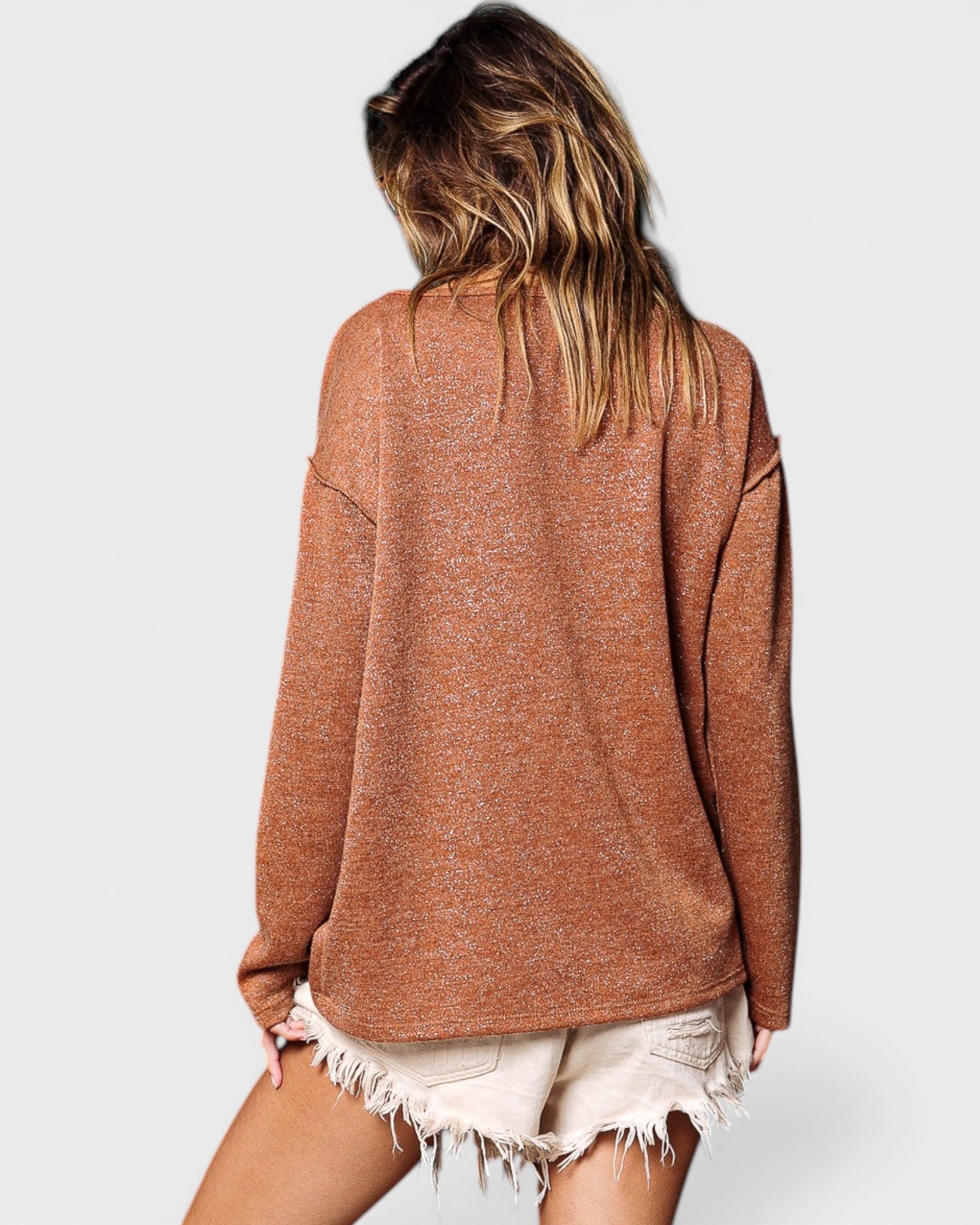Person wearing a brown sweater and white shorts on a plain background