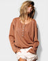 Woman wearing a brown long-sleeve top and white shorts against a light background
