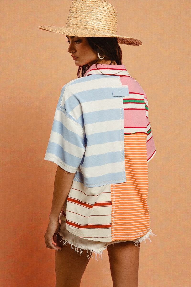 Woman wearing a colorful striped shirt and straw hat against a peach background