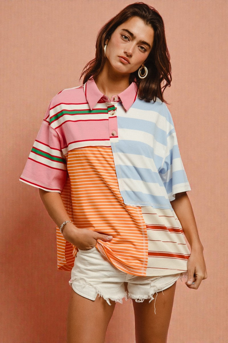 Woman wearing a colorful striped shirt and white shorts against a pink background