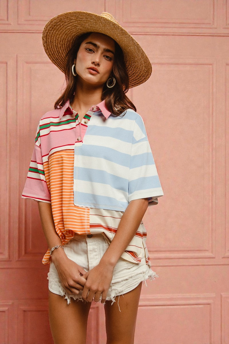 Woman wearing a colorful striped shirt and straw hat against a pink textured wall