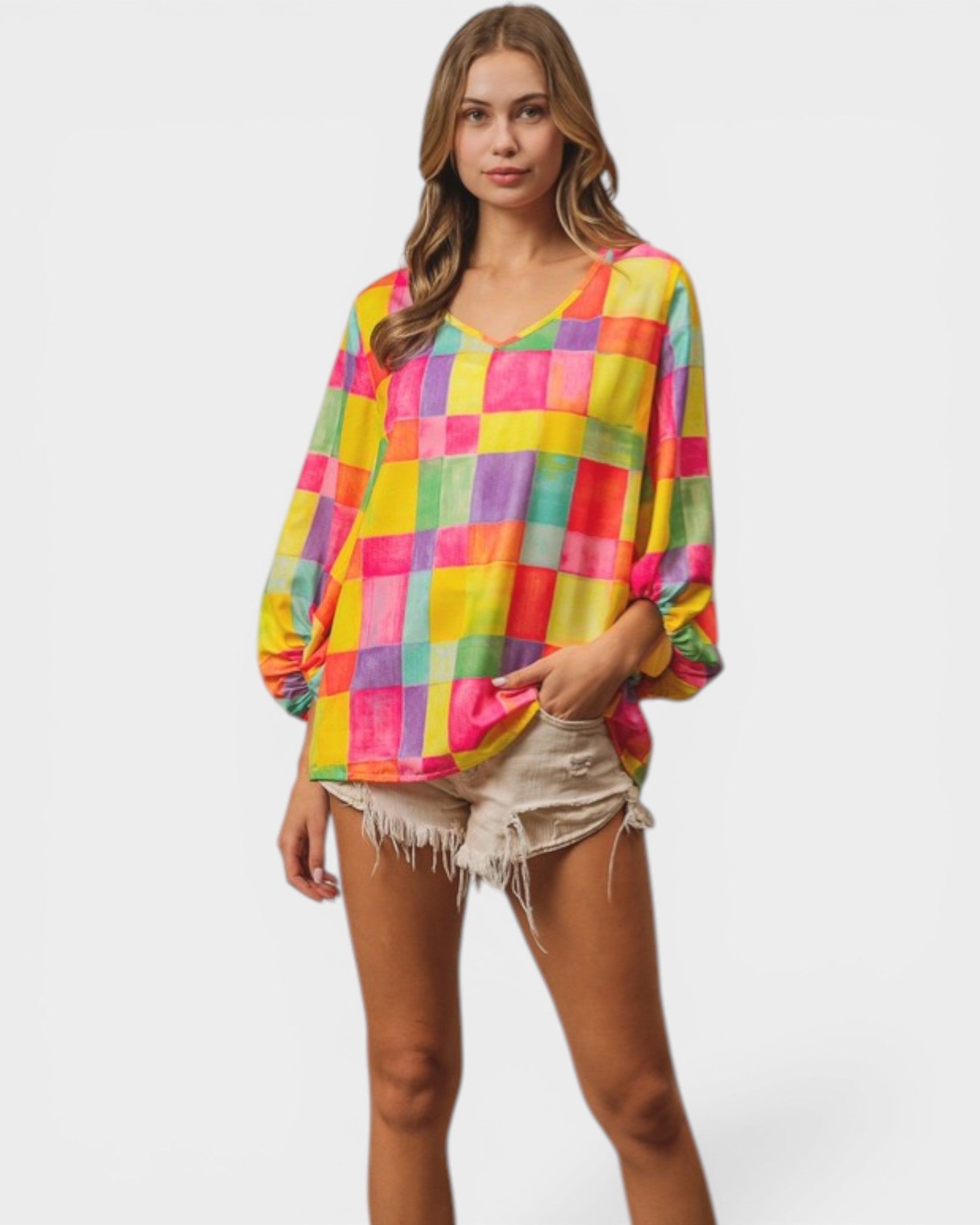 Woman wearing a colorful checkered blouse and denim shorts on a white background
