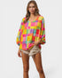 Woman wearing a colorful checkered blouse and denim shorts on a white background