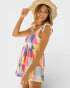 Woman wearing a colorful geometric-patterned dress and straw hat on a white background