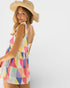 Woman wearing a colorful geometric-patterned dress and straw hat on a white background