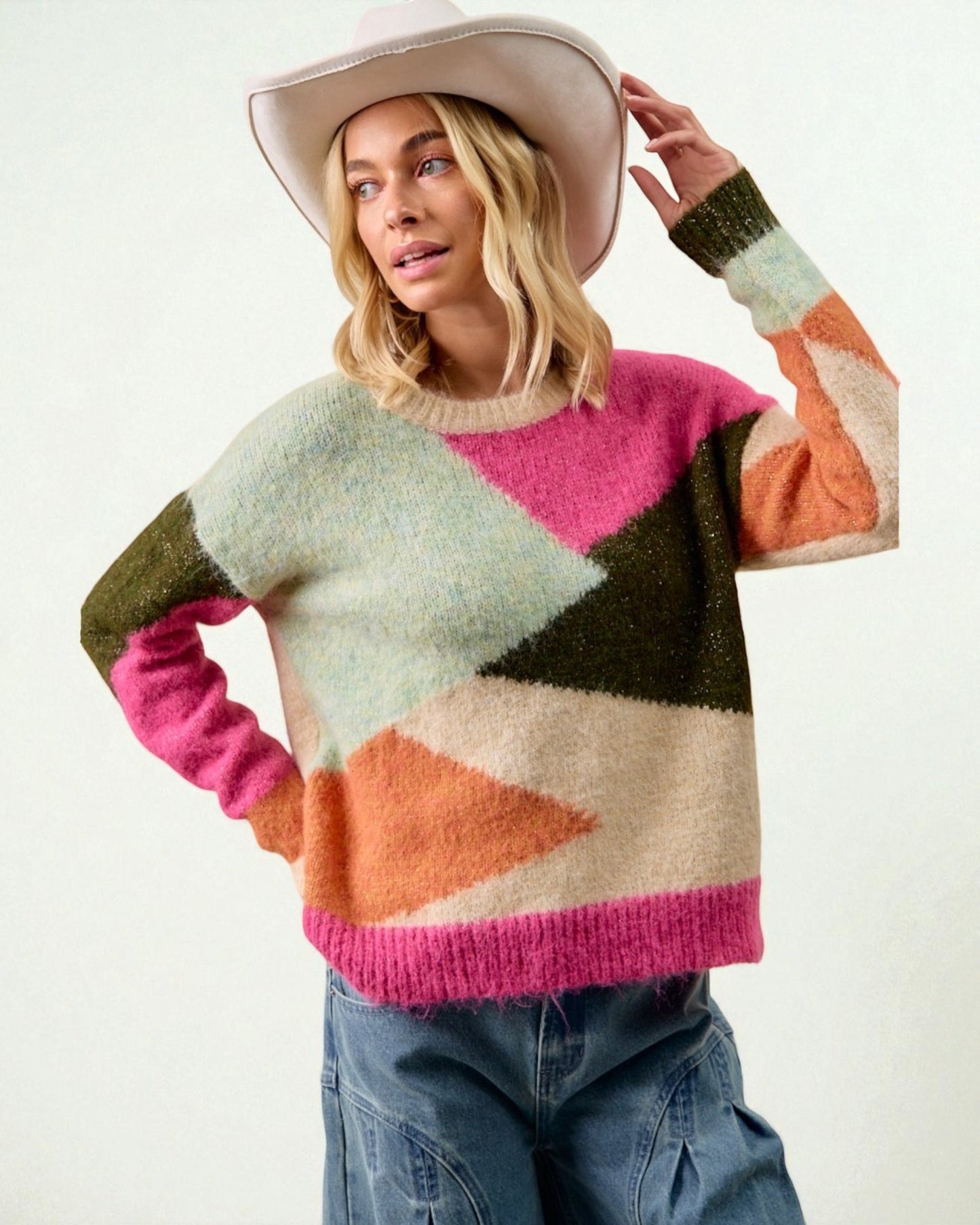 Woman wearing a colorful sweater with geometric pattern and a white hat on a light background