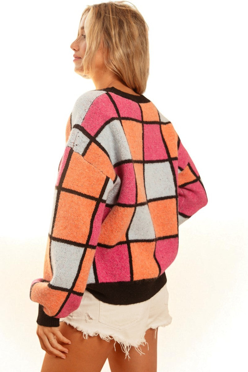Woman wearing a colorful geometric-patterned sweater on a white background