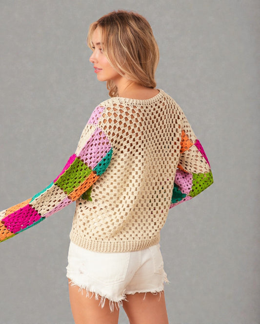 Woman wearing a colorful crochet sweater against a gray background