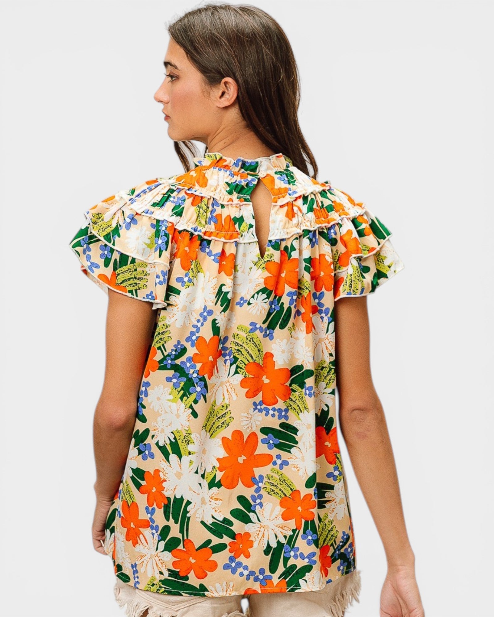Woman wearing a colorful floral blouse on a plain background