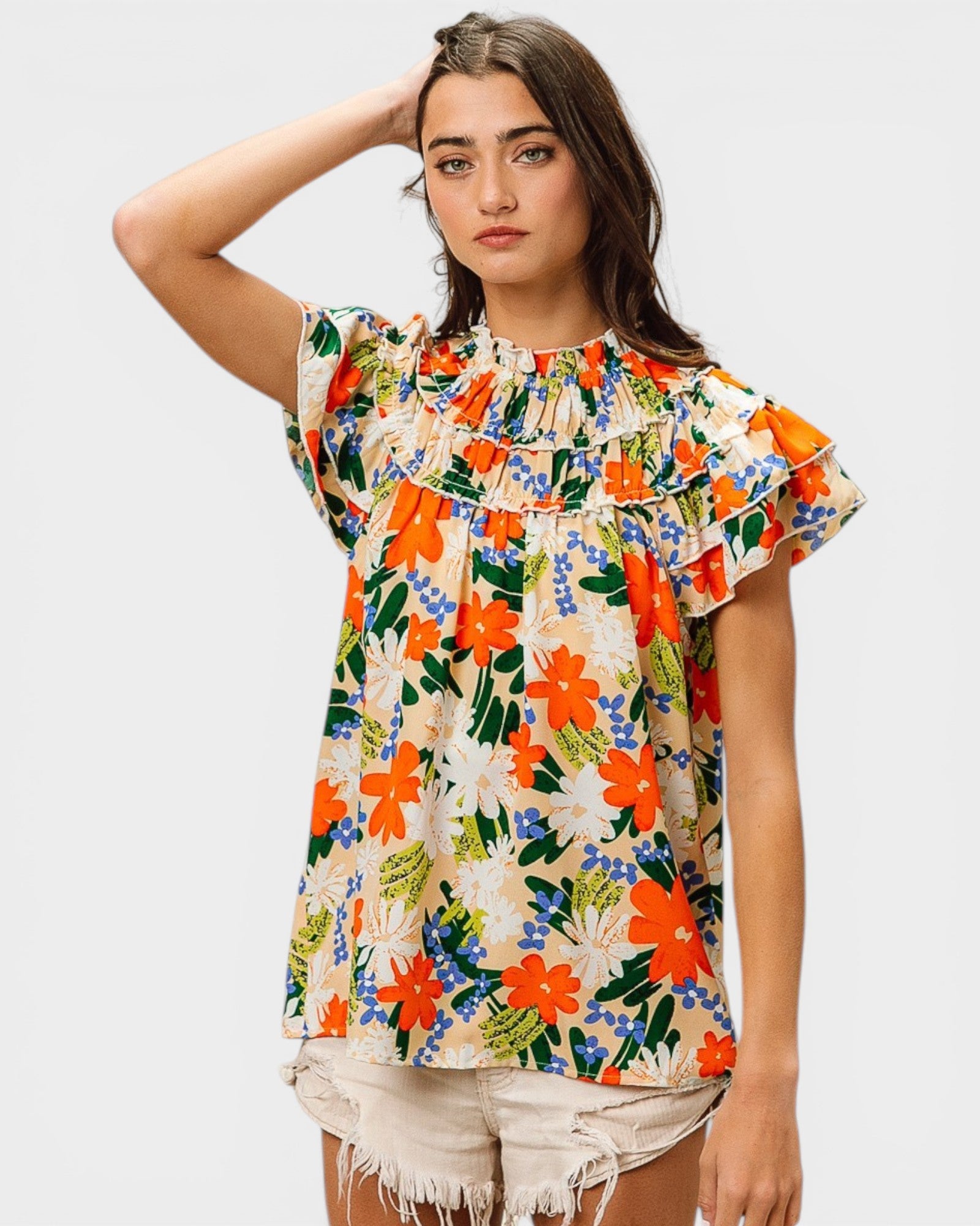 Woman wearing a colorful floral blouse with ruffled sleeves on a white background