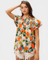 Woman wearing a colorful floral blouse with ruffled sleeves on a white background