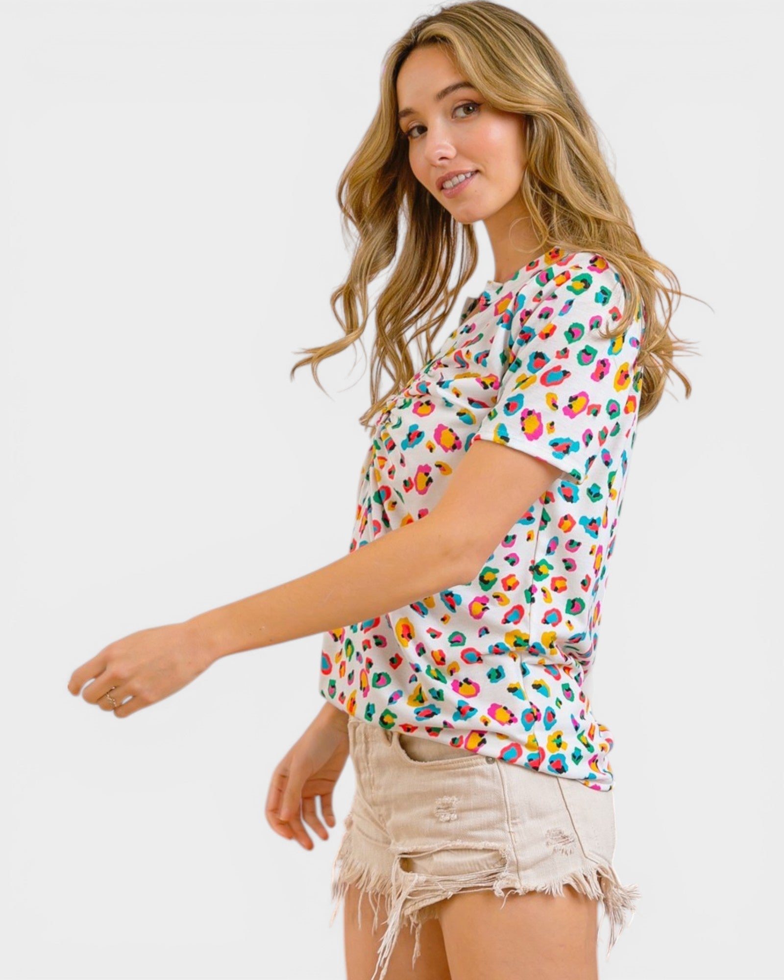 Woman wearing a colorful patterned shirt and beige shorts on a white background