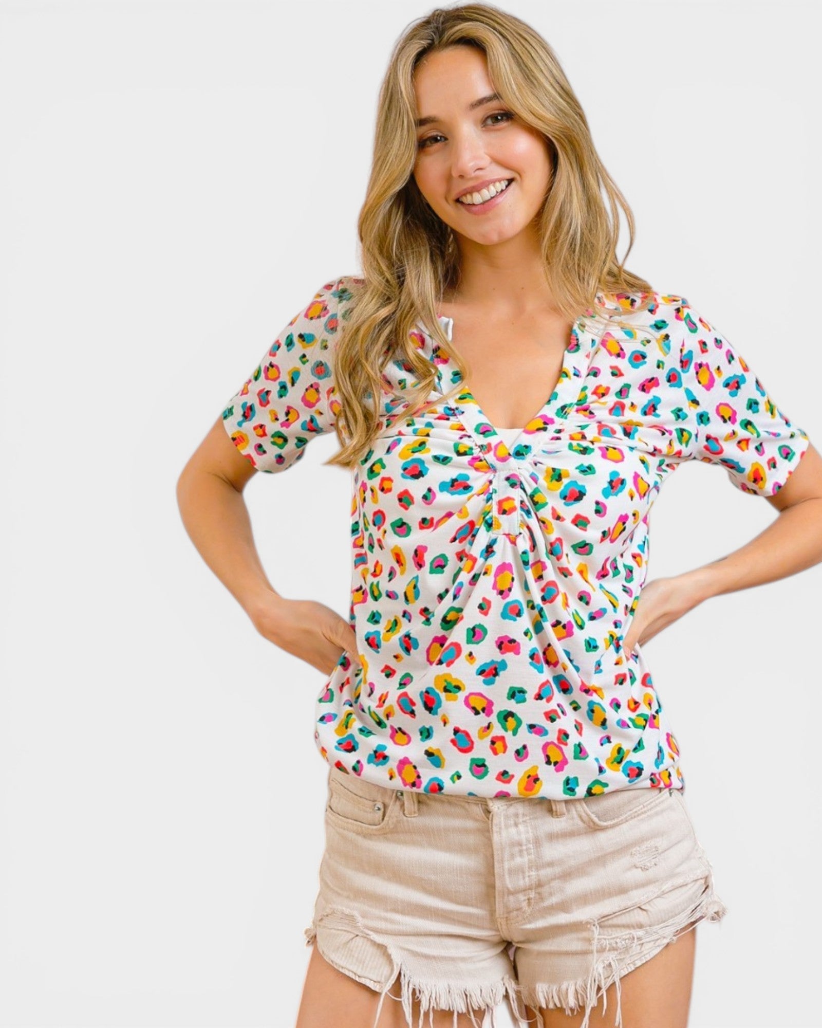 Woman wearing a colorful patterned top and beige shorts on a white background