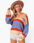A woman wearing a colorful striped off-the-shoulder knit sweater, white denim shorts, and a brown wide-brim straw hat, posed against a clean white studio background.