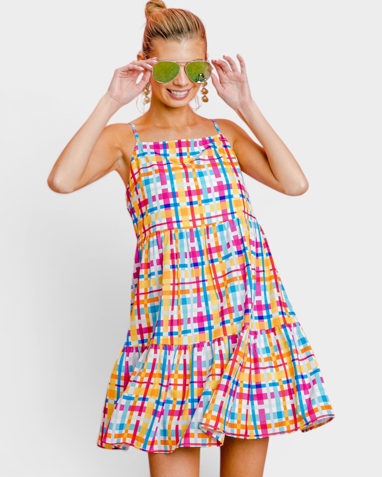Woman wearing a colorful plaid dress with sunglasses on a white background