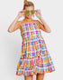 Woman wearing a colorful plaid dress with sunglasses on a white background