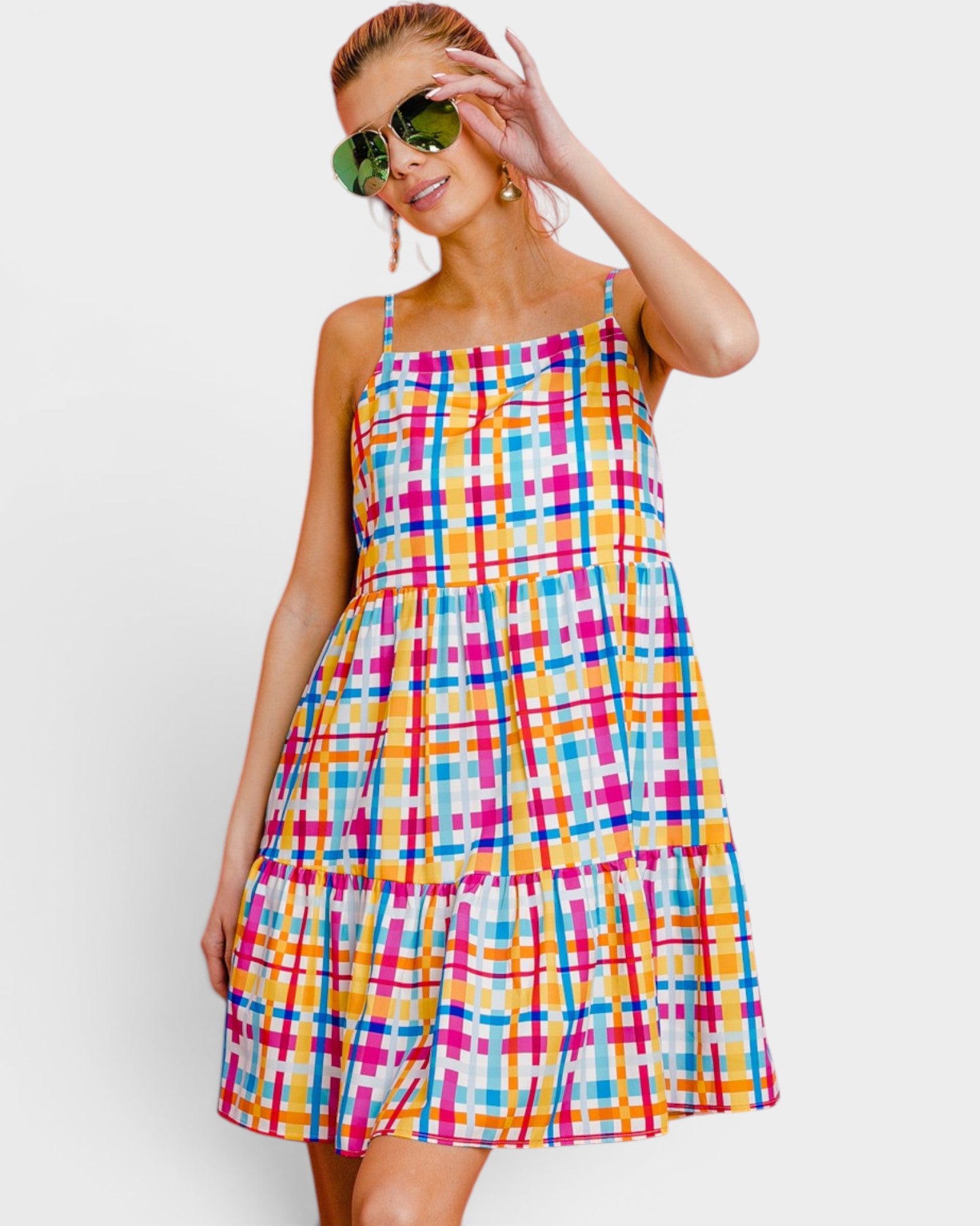 Woman wearing a colorful plaid dress with sunglasses on a white background
