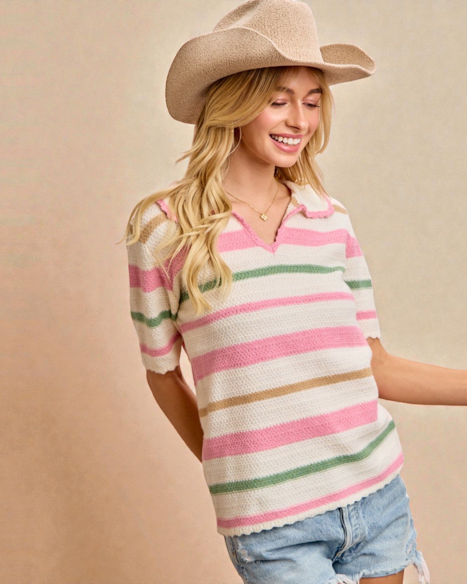 Woman wearing a striped sweater and cowboy hat against a beige background