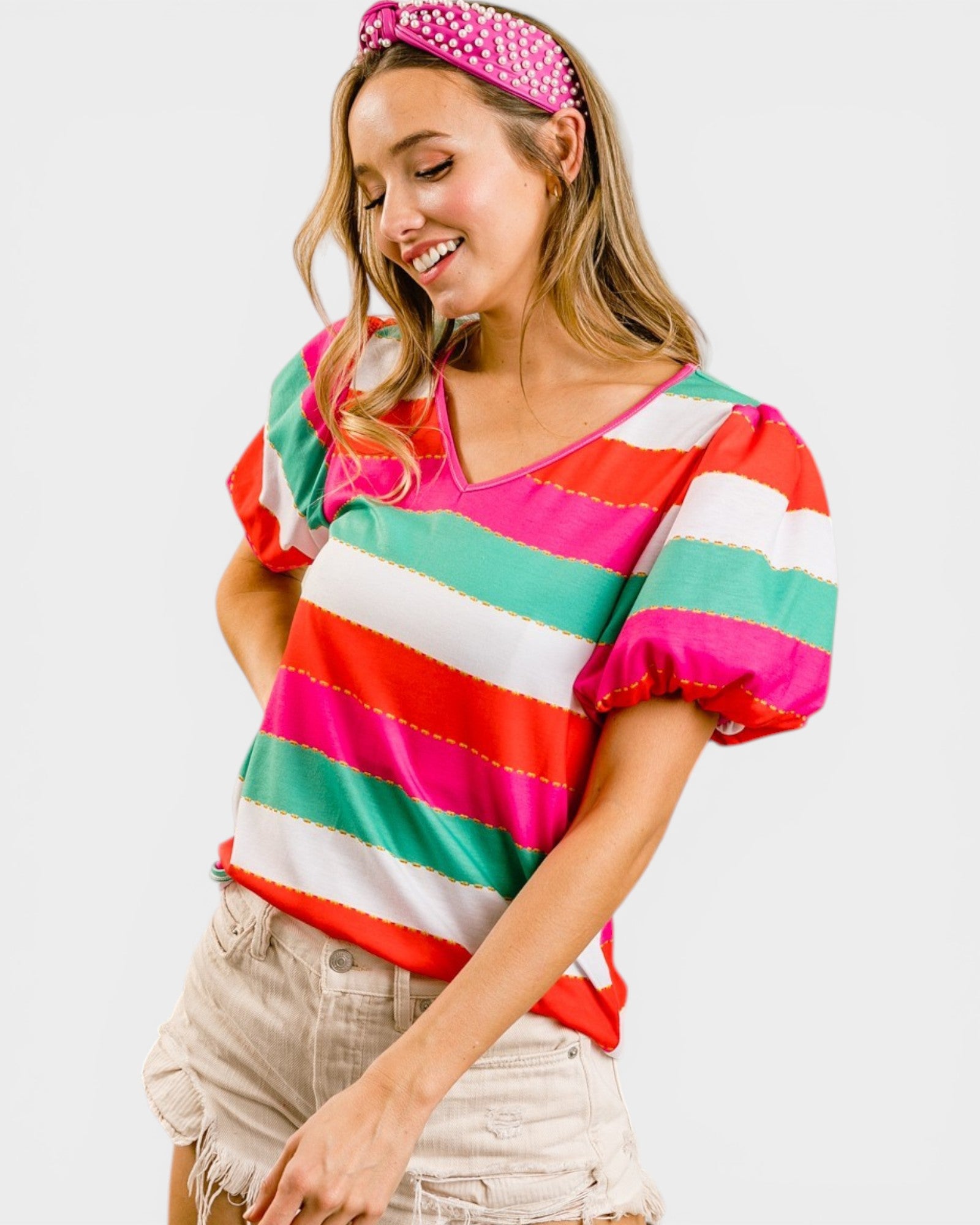 Woman wearing a colorful striped shirt and pink headband on a white background