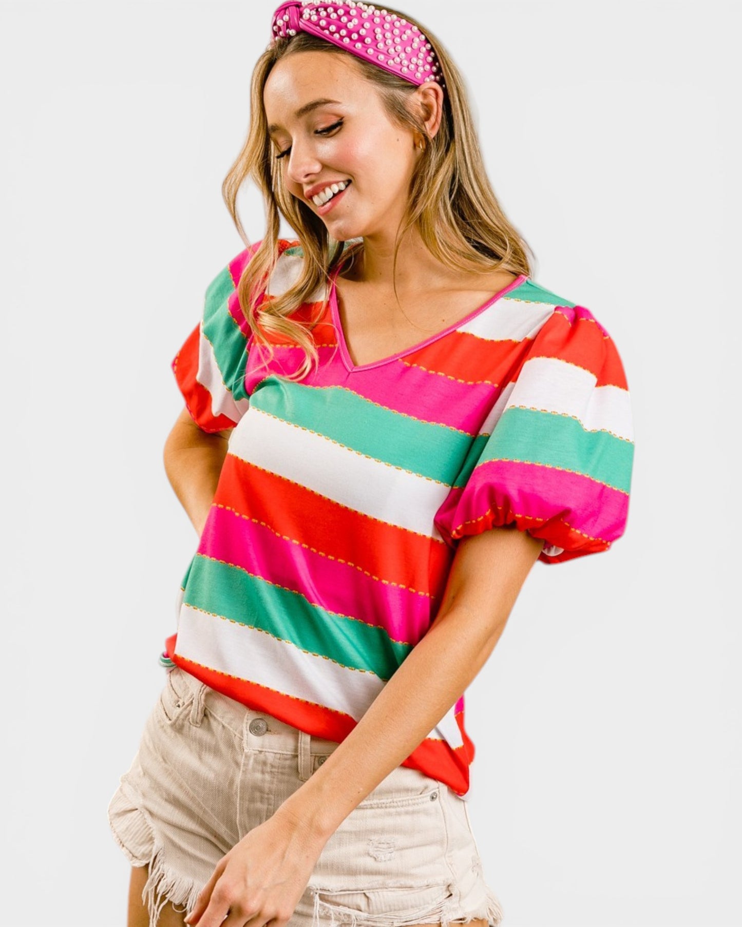 Woman wearing a colorful striped shirt and pink headband on a white background