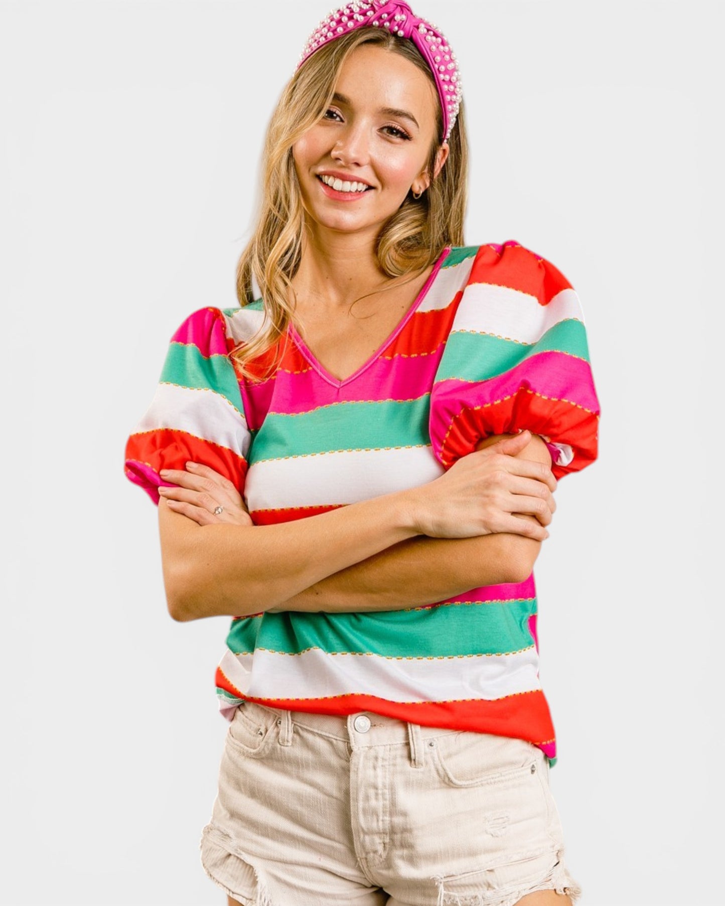 Woman wearing a colorful striped shirt and pink headband on a white background