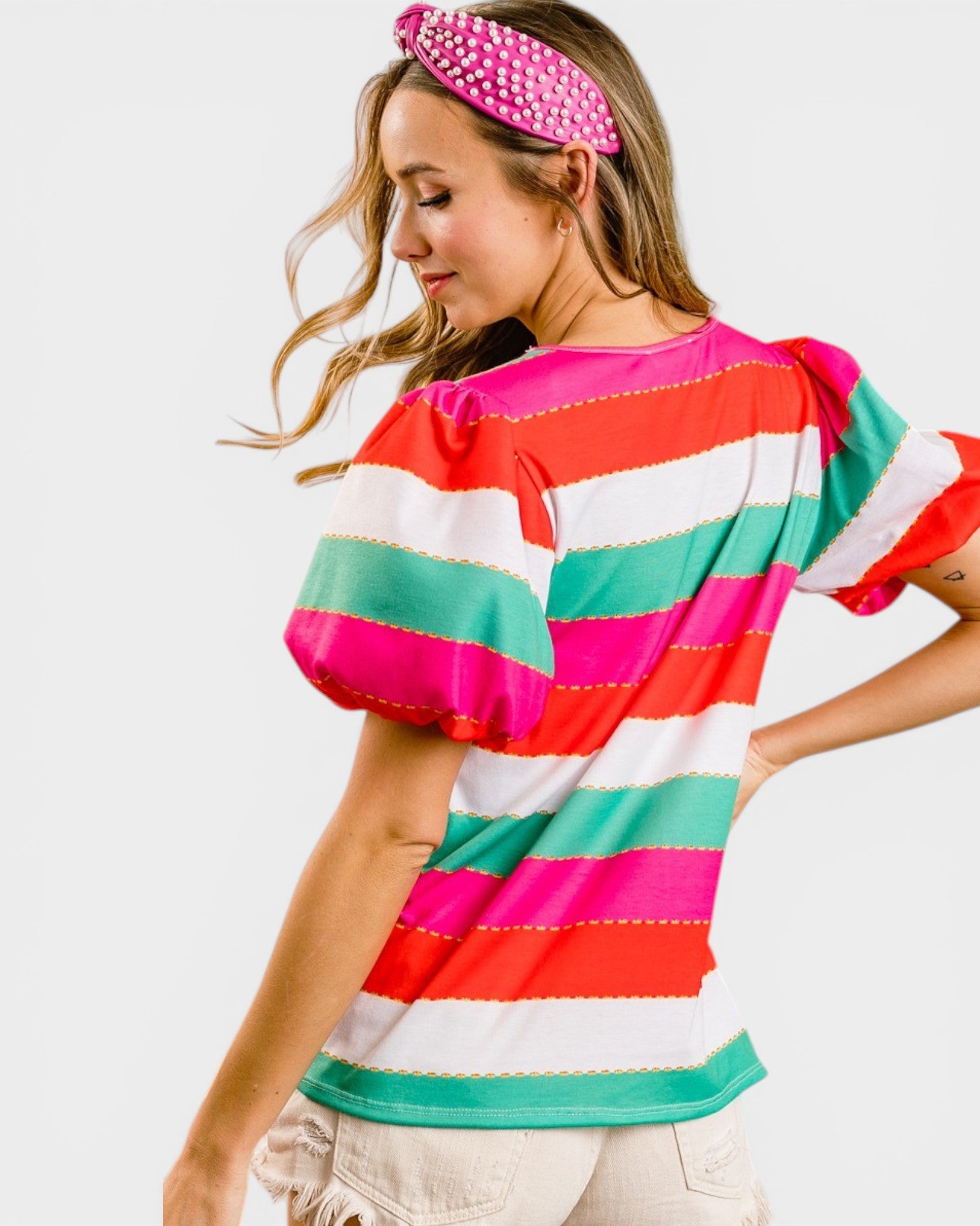 Woman wearing a colorful striped shirt with a pink headband on a white background