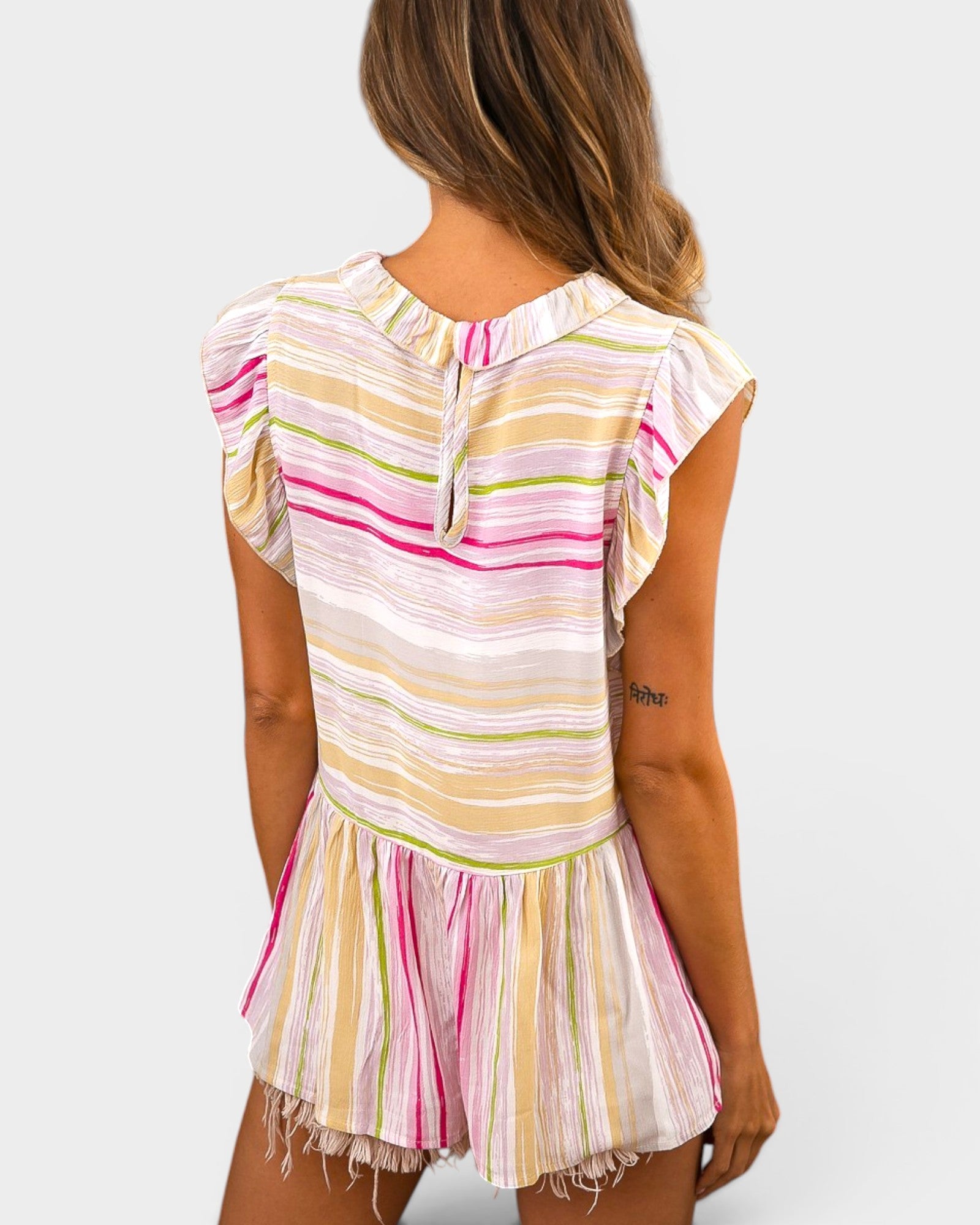 Woman wearing a colorful striped dress on a plain background