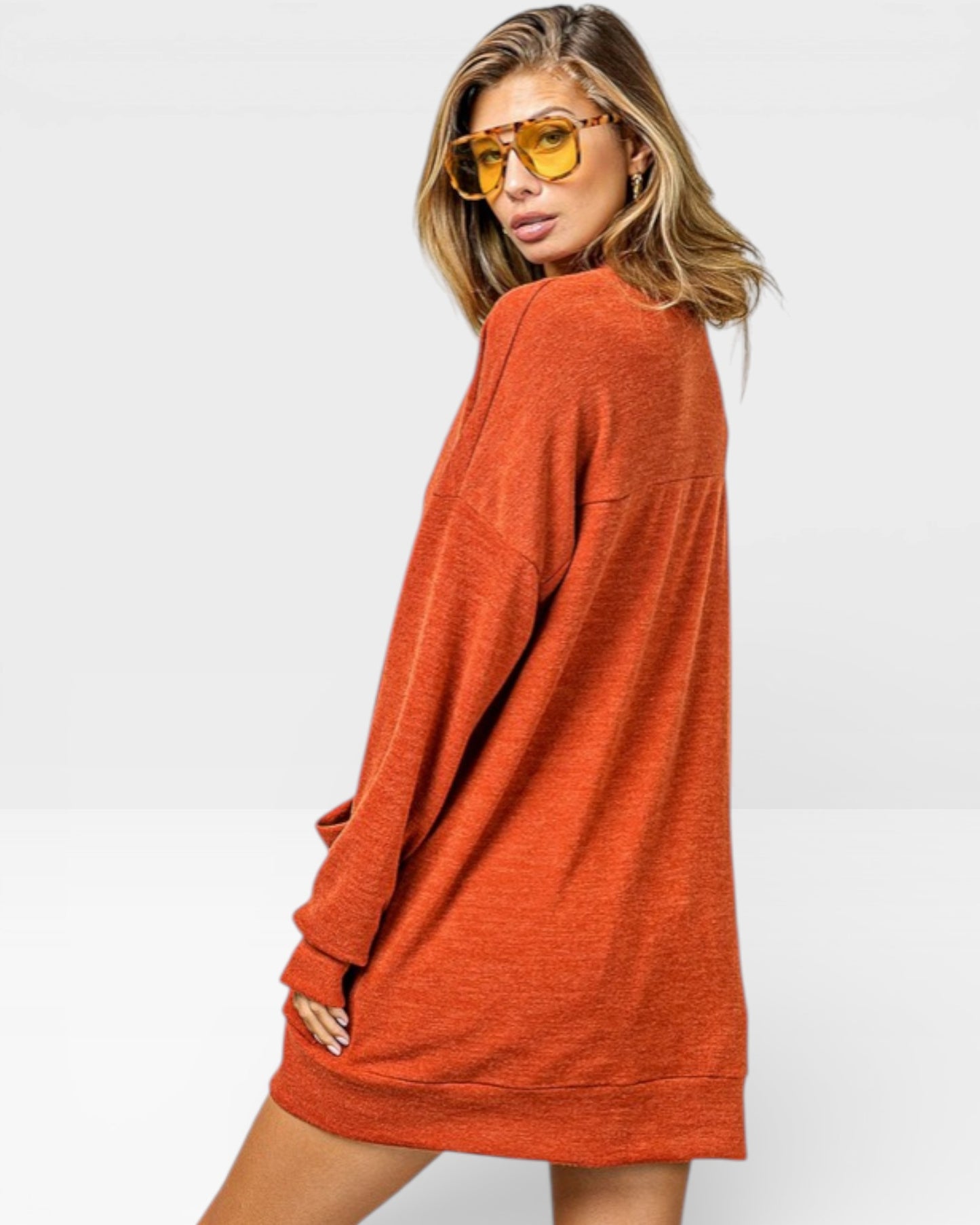 Woman wearing a rust-colored long-sleeve dress against a white background