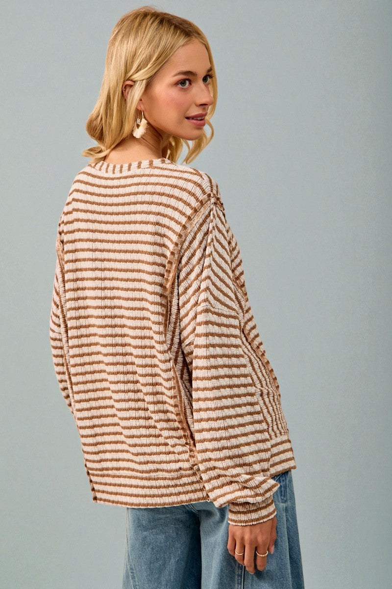 Woman wearing a striped sweater and jeans against a gray background