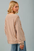 Woman wearing a striped sweater and jeans against a gray background