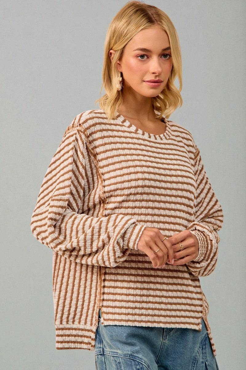 Woman wearing a striped sweater and jeans against a gray background