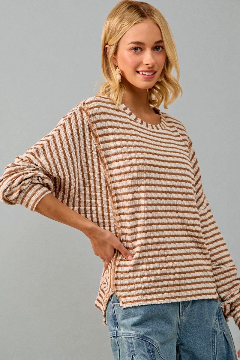 Woman wearing a striped sweater and jeans against a gray background