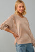 Woman wearing a striped sweater and jeans against a gray background