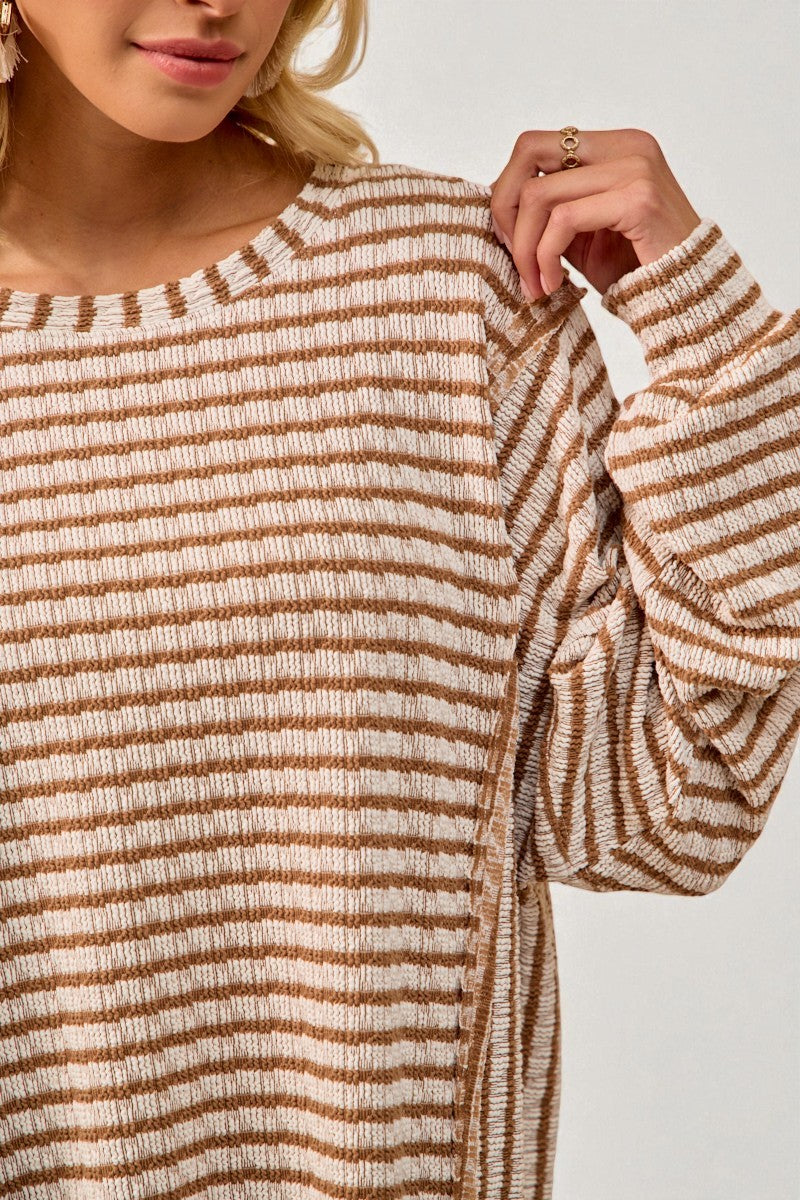 Close-up of a person wearing a brown and beige striped sweater against a neutral background